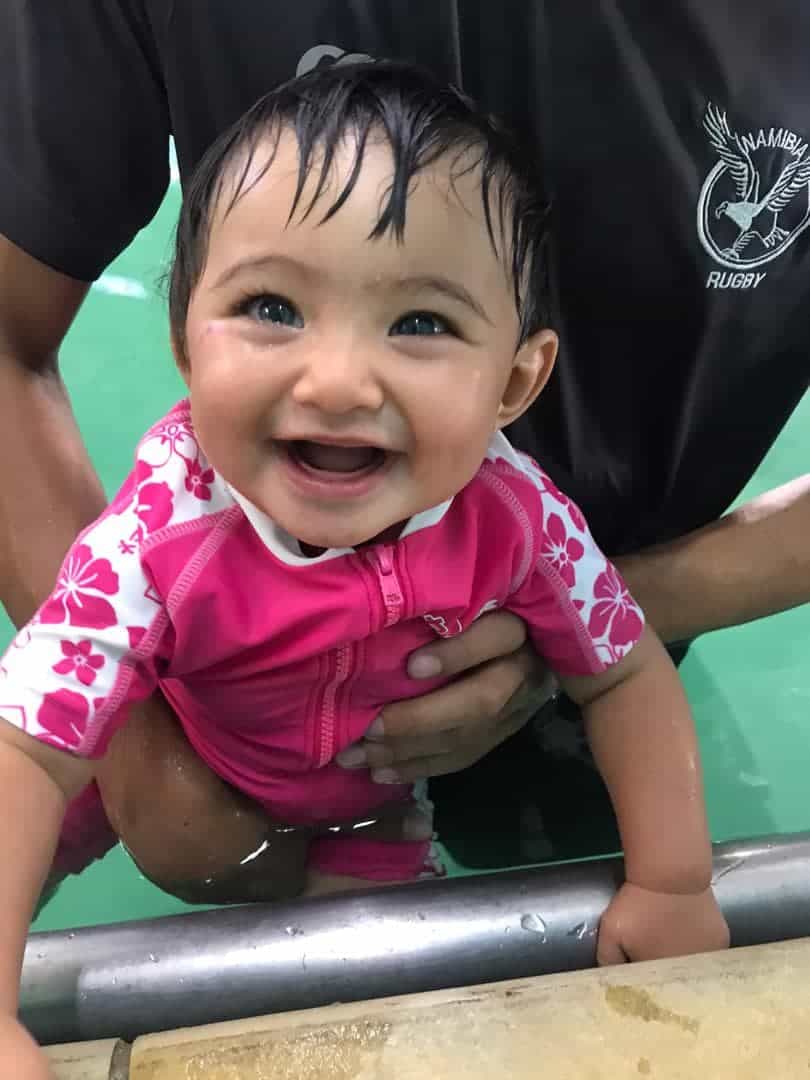 Baby smiling in swimming pool.